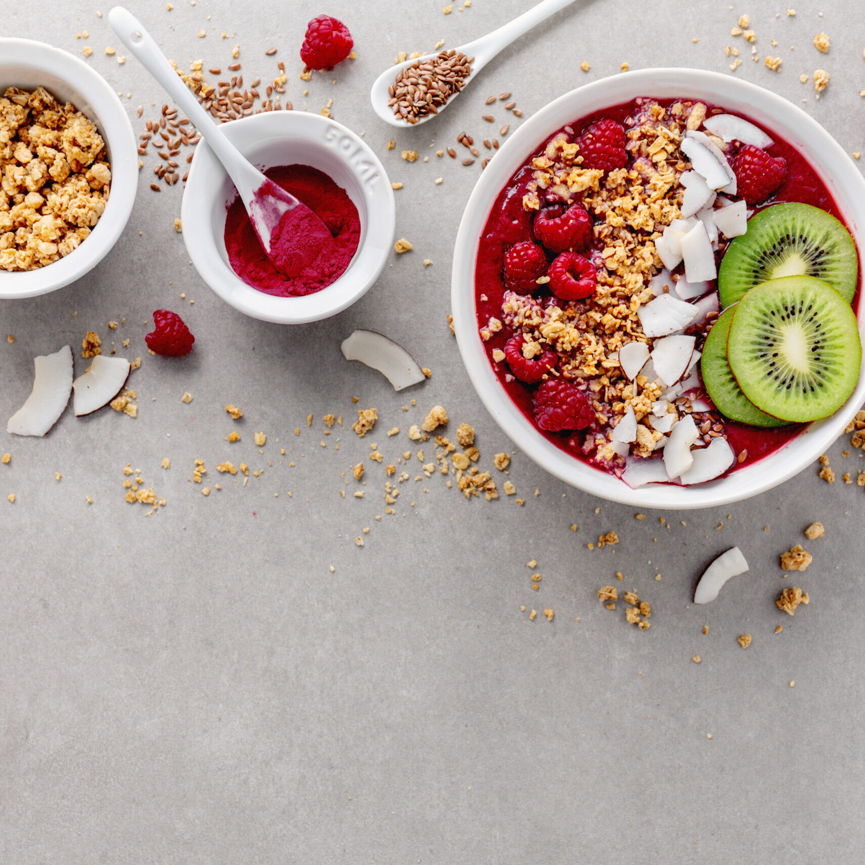Tasty appetizing homemade smoothie bowl made from fresh berries, served with muesli granola and coconut flakes. Grey background. Top View with Copy Space.